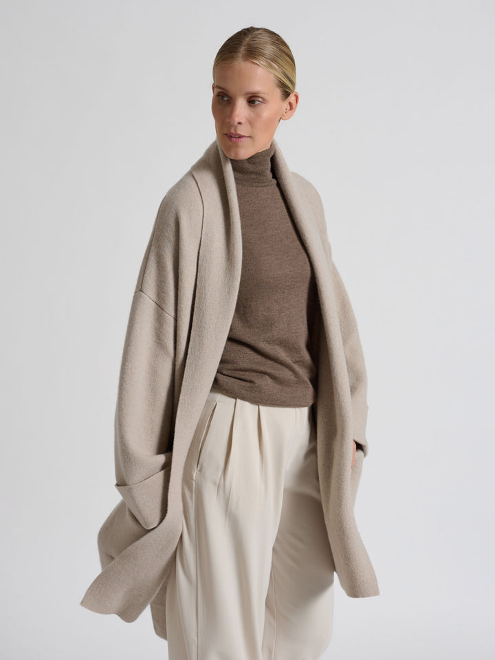 Woman wearing a brown turtleneck sweater against a gray background. Turtleneck cashmere t-shirt "Agnes" in 100% pure cashmere. Scandinavian design by Kashina. Color: Dark Toast.