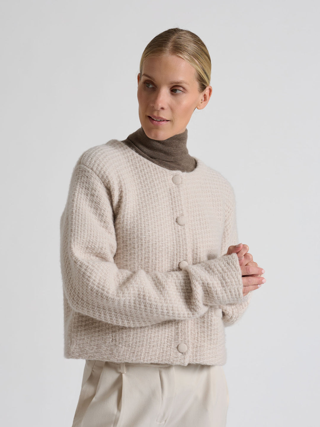 Woman wearing a brown turtleneck sweater against a gray background. Turtleneck cashmere t-shirt "Agnes" in 100% pure cashmere. Scandinavian design by Kashina. Color: Dark Toast.