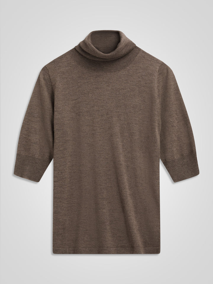 Woman wearing a brown turtleneck sweater against a gray background. Turtleneck cashmere t-shirt "Agnes" in 100% pure cashmere. Scandinavian design by Kashina. Color: Dark Toast.
